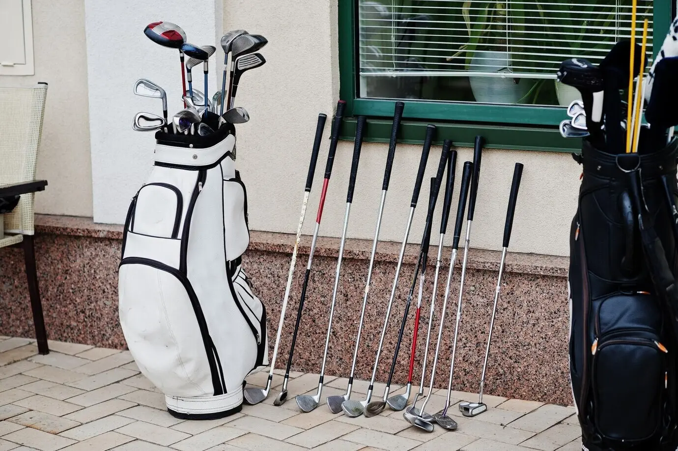 A bag on the pavement containing many golf clubs.