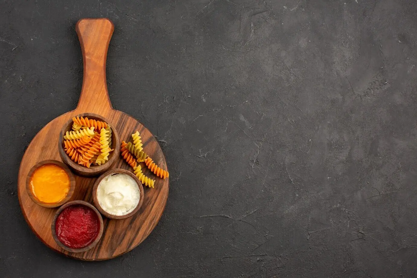 Top view of cooked Italian pasta, unusual spiral pasta with seasonings, on a dark background.